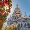 Vue artistique du Sacré-Cœur de Montmartre à Paris en automne avec un rayon de soleil à travers les feuilles.