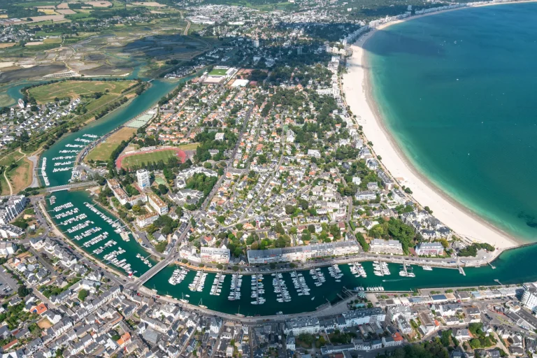 Vue aérienne de la station balnéaire de La Baule avec sa plage en arc de cercle, ses marinas, ses habitations et les marais à l’arrière-plan.